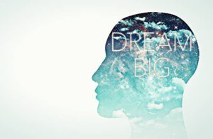 A double exposure of the head and sky with words " dream big ".